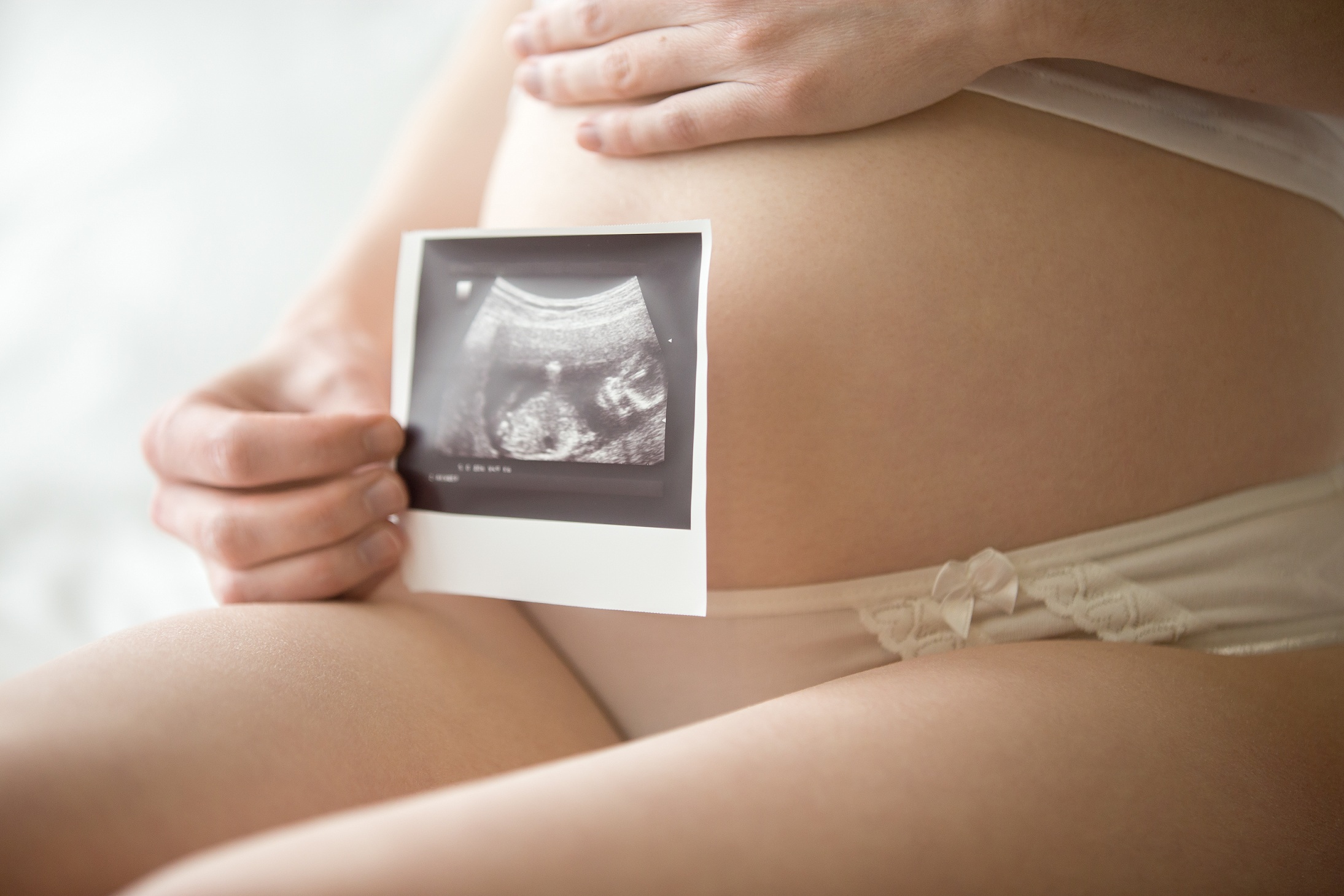 Kobieta w ciąży pokazująca zdjęcie zarodka po USG